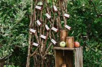 an apple orchard wedding seating plan with lots of branches, greenery and berries and some escort cards, crates with apples around