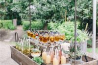an elegant vintage bar cart of reclaimed wood, with chic wheels, a roof and lots of drinks and potted greenery and succulents