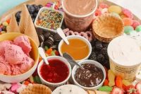 an ice cream board with candies, fresh berries, fresh toppings, ice cream and waffle cones plus cookies is amazing for a modern wedding