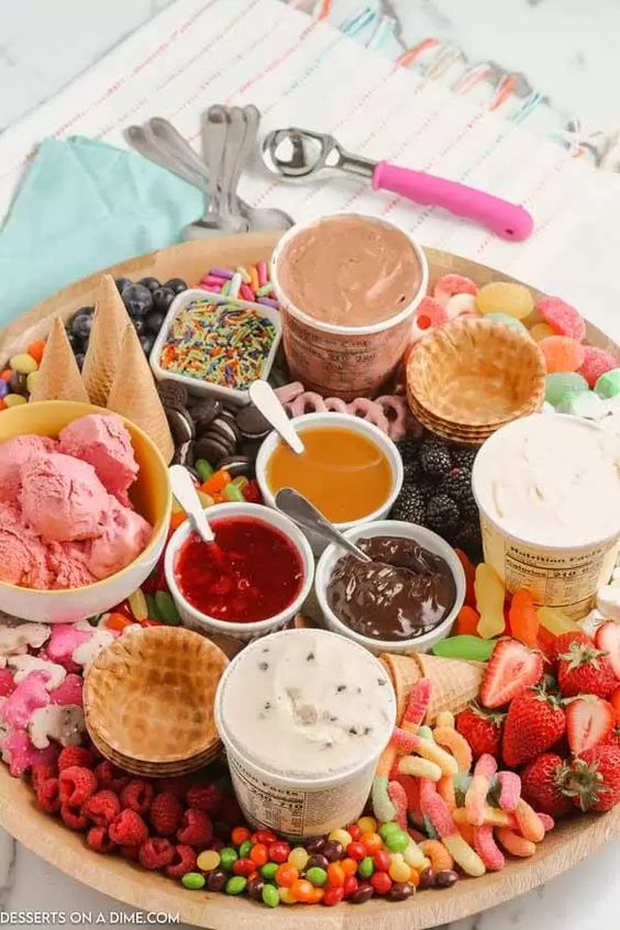 an ice cream board with candies, fresh berries, fresh toppings, ice cream and waffle cones plus cookies is amazing for a modern wedding