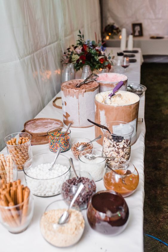 an ice cream table with lots of toppings, waffles and several types of ice cream in very large jars is perfect for a wedding