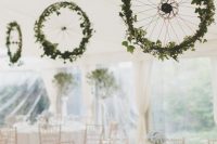 bike wheels decorated with greenery are a fresh and creative decor idea for a neutral wedding reception space