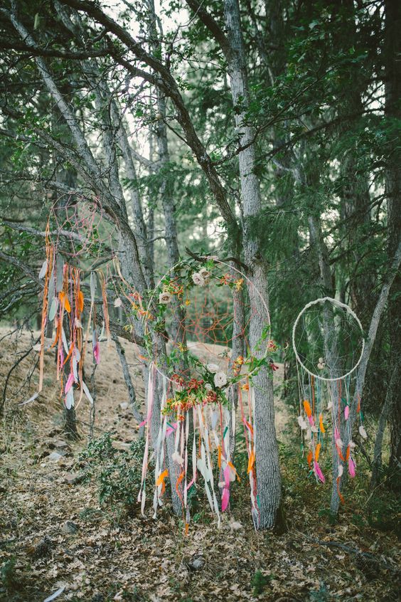 Super colorful boho dream catchers decorated with greenery and bright flowers, with long colorful ribbons and feathers