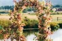 a beautiful and bright fall wedding arch of pink, blush and neutral blooms, including dahlias and hydrangeas, greenery and bold foliage is a very cool and cheerful idea