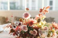 a beautiful and bright wedding centerpiece of rust, dusty pink and coral blooms, bold fall leaves is a very refined idea