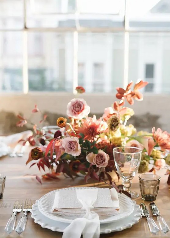 a beautiful and bright wedding centerpiece of rust, dusty pink and coral blooms, bold fall leaves is a very refined idea