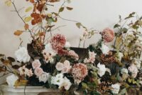 a beautiful fall wedding arrangement of greenery, white and blush blooms and bold fall foliage is adorable for a fall wedding