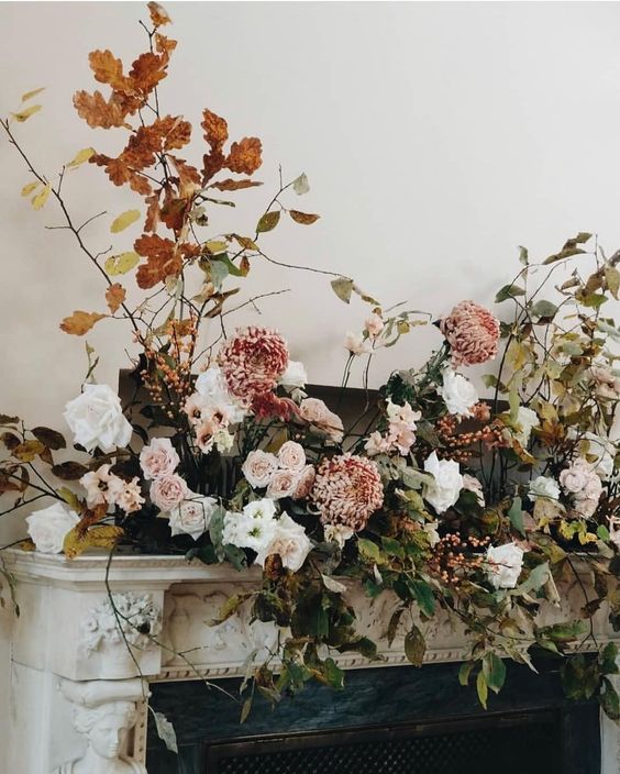 a beautiful fall wedding arrangement of greenery, white and blush blooms and bold fall foliage is adorable for a fall wedding