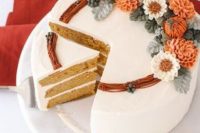 a beautiful pumpkin spice wedding cake covered with white buttercream, with bright sugar blooms and pumpkins, with sugar leaves