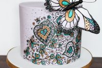 a beautiful wedding cake with painted heart and floral patterns and a giant butterfly on top is a gorgeous statement idea
