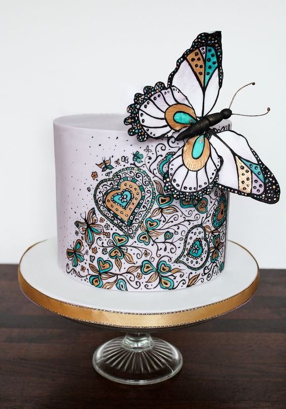 a beautiful wedding cake with painted heart and floral patterns and a giant butterfly on top is a gorgeous statement idea