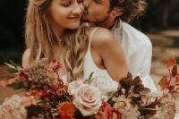 a bold and lush fall wedding bouquet of blus, rust, deep red blooms, greenery and dark foliage, grasses is a lovely idea for a boho fall wedding