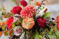 a bold and textural wedding centerpiece of red, mauve, rust and blush blooms, greenery, foliage for a fall celebration