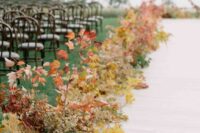a bold fall wedding aisle with a runner and bright fall leaves and dried flowers is a cool idea for an autumn wedding