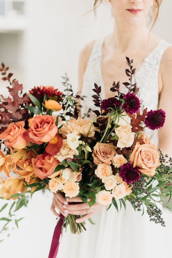 a bold fall wedding bouquet of blush, rust, mustard, purple blooms, greenery, privet berries and bold foliage is wow