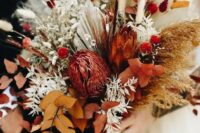a bold fall wedding bouquet of rust and burgundy blooms, bold fall foliage, fronds, bunny tails and grasses is fantastic