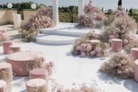 a breathtaking wedding ceremony space with a creative altar in white, pink blooms around and pink ottomans and poufs