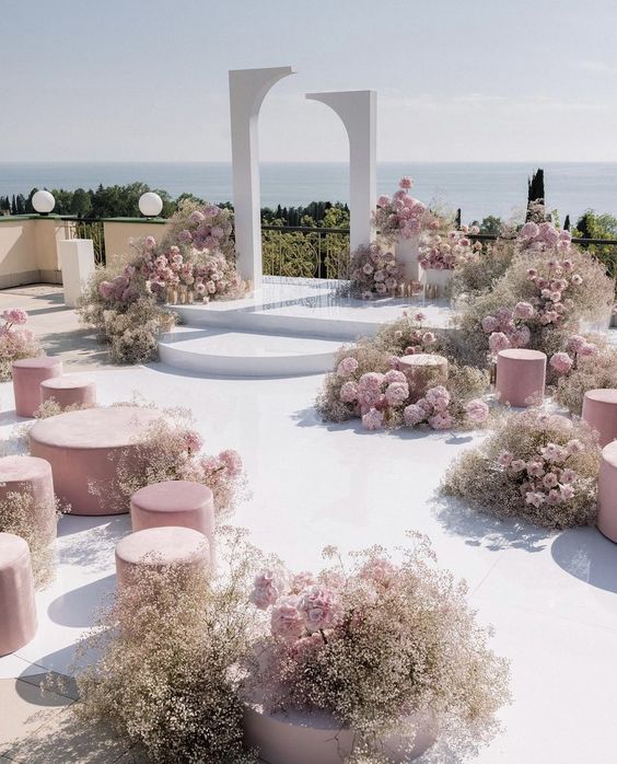 a breathtaking wedding ceremony space with a creative altar in white, pink blooms around and pink ottomans and poufs