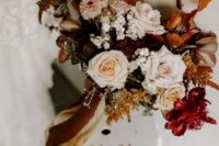 a bright fall wedding bouquet of blush, deep red and rust blooms, colorful fall foliage and bold ribbons is a very cool and chic idea for a boho wedding