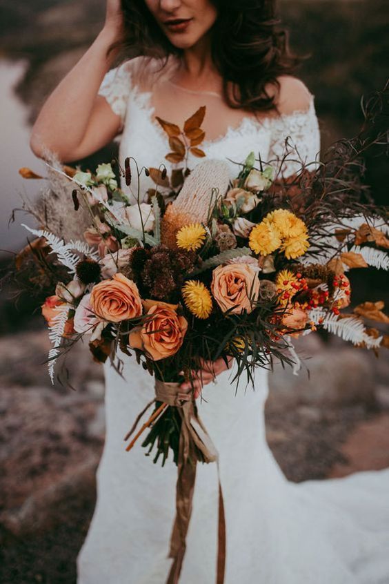 a bright fall wedding bouquet of blush, yellow blooms, dark foliage, dried leaves and greenery is a cool and chic idea