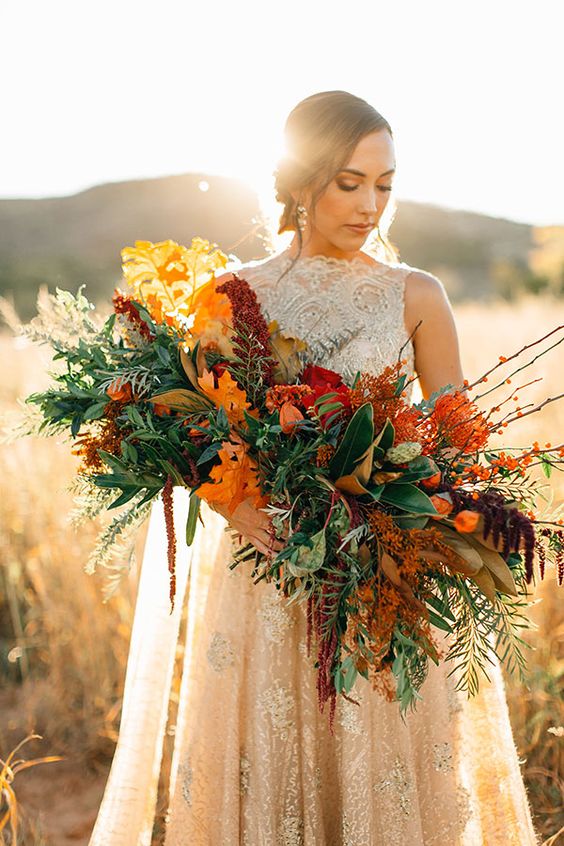 a bright fall wedding bouquet of greenery, bold fall foliage, twigs and leaves plus berries is adorable for a fall wedding