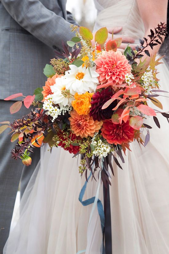 a bright fall wedding bouquet of white, pink, orange and burgundy blooms and bold fall foliage is amazing for a fall wedding