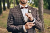 a brown plaid three-piece pantsuit, a white shirt, a brown bow tie and a simple white flower boutonniere for a fall wedding