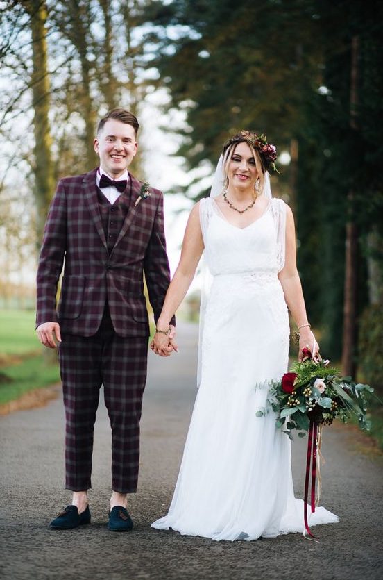 a burgundy checked three-piece wedding suit, a white shirt, a burgundy velvet bow tie and teal tassel loafers