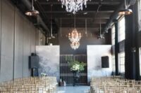 a chic and bold wedding ceremony space with white chairs, petals and pillar candles, crystal chandeliers