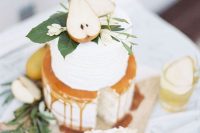 a chic white wedding cake with caramel, foliage and white blooms and cut pears is a fantastic idea for a fall wedding