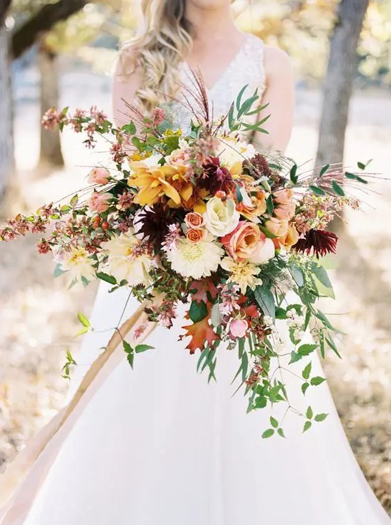 a colorful and dimensional fall bouquet with yellow, pink, white, red flowers and greenery and red leaves plus a cascade for a catchier look