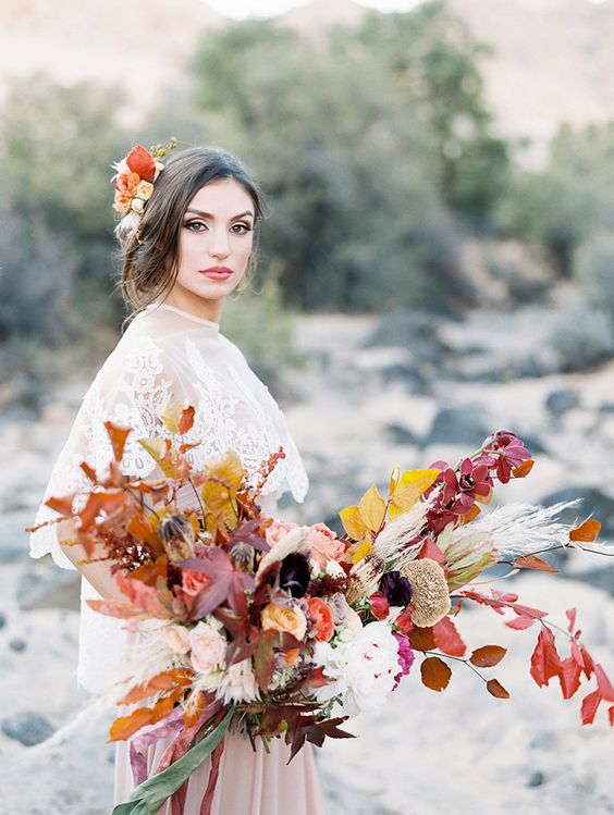 a colorful fall wedding bouquet of white and blush blooms, yellow and burgundy leaves and pampas grass is wow