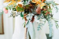 a colorful fall wedding bouquet of yellow and pink roses, greenery, bold foliage and berries is amazing for the fall