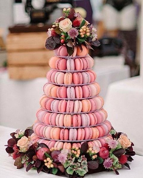 a colorful macaron tower with peachy, lavender and bright pink macarons, with colorful blooms and dark foliage is a fantastic idea for a summer wedding