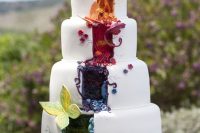 a colorful wedding cake in all the shades of the rainbow, with butterflies, flowers and feathers and painted patterns here and there