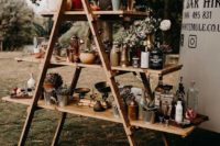 a cool outdoor wedding bar of a ladder, succulents and greenery, various drinks and glasses