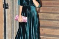 a dark green velvet midi dress with long sleeves, a pleated skirt, a deep V-neckline, pink shoes and a pink clutch