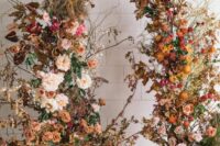 a dreamy fall wedding arch with blush and bold blooms, greenery and bright and dried fall leaves is chic
