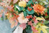 a fall leaf and bloom wedding bouquet with dahlias, fall leaves and berries plus a blush ribbon