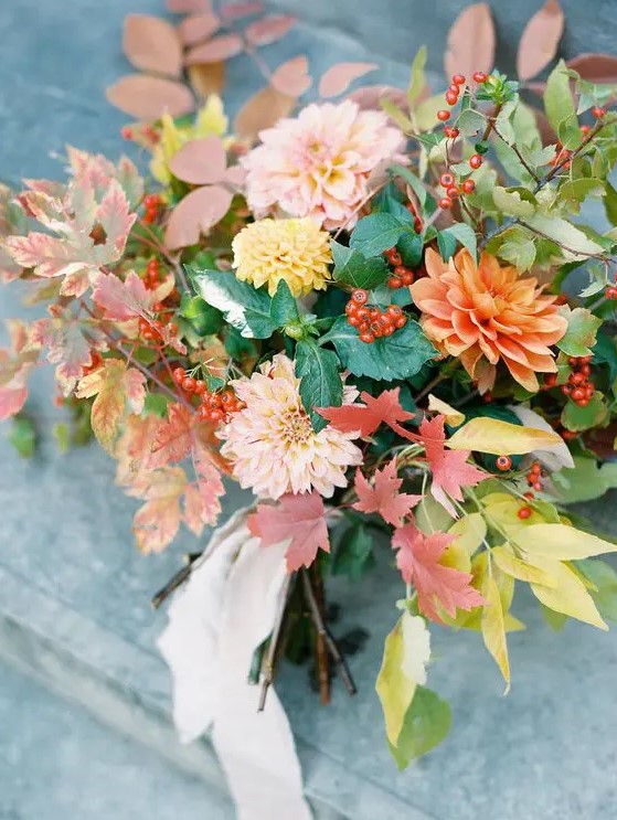a fall leaf and bloom wedding bouquet with dahlias, fall leaves and berries plus a blush ribbon