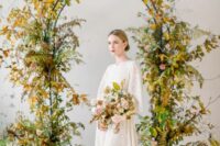 a fall wedding arch covered with greenery and gold fall leaves is a chic and stylish idea for a fall wedding