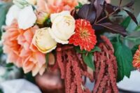 a fall wedding centerpiece of white roses, red mums, pink dahlias, dark foliage and greenery and amaranthus is a cool idea