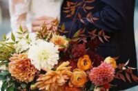 a fantastic colorful fall wedding bouquet of orange, rust, pink, white and burgundy flowers, greenery and bold fall foliage