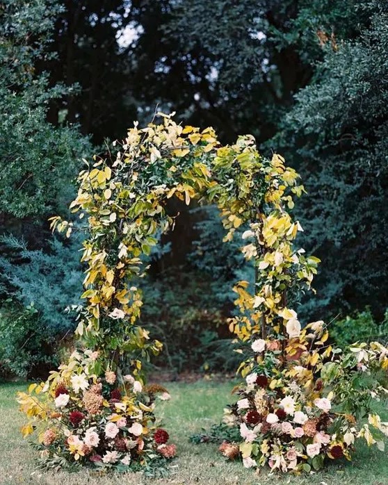 a fantastic fall wedding arch decorated with greenery and yellow leaves, blush, white and burgundy dahlias for a wow effect