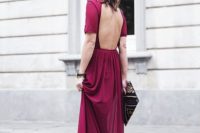 a fuchsia maxi dress with an open back, short sleeves and a patterned clutch for a formal fall wedding guets look