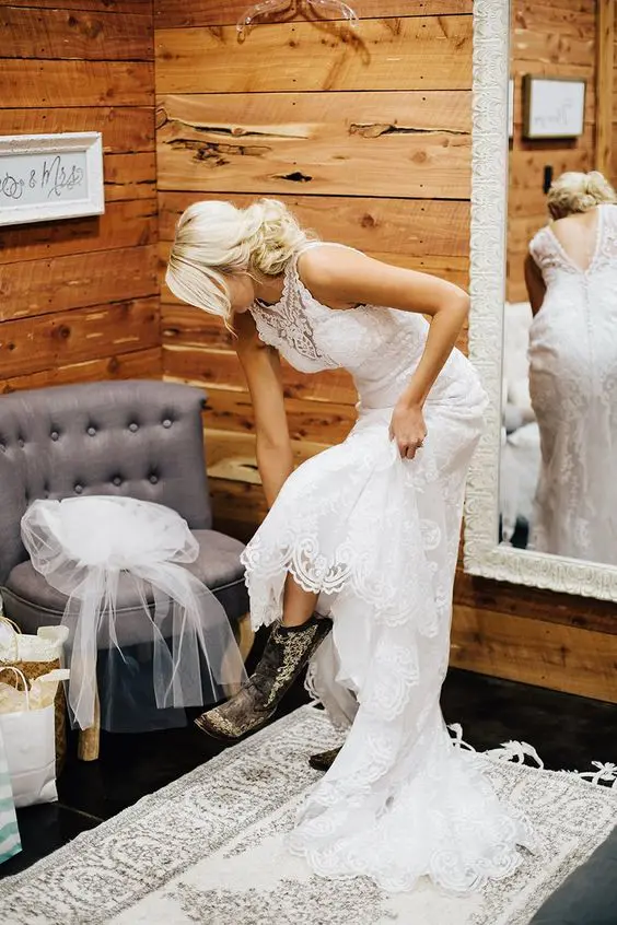 a glam bridal look with a lace fitting wedding dress with a high neckline and a train, brown patterned cowgirl boots