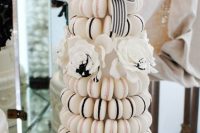 a glam white macaron tower with black and pink filling, with a white bloom and a striped ribbon is a cool idea