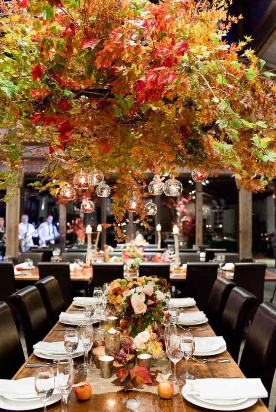 a gorgeous oversized fall leaf hanging over the reception with candles looks fall-like like no other