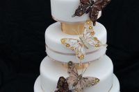 a gorgeous wedding cake in white, with tan ribbons, gold touches and beautiful and refined butterflies for decor