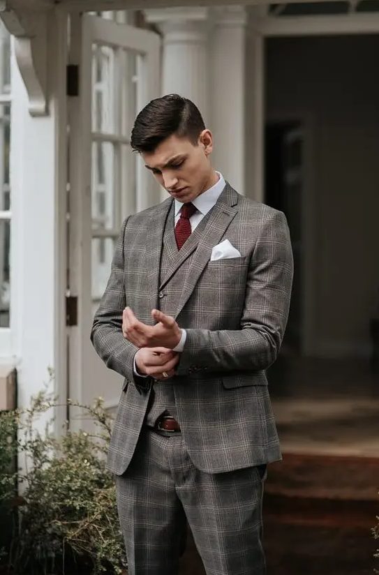 a grey plaid three-piece suit, a white shirt, a burgundy bow tie and a brown belt for a touch of vintage